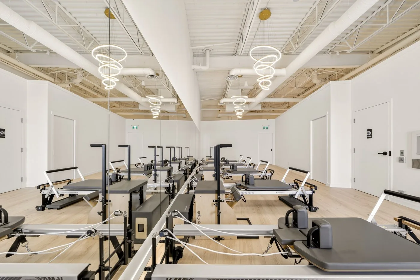 The Reformer room at Elin Pilates — Merrithew reformers under ring chandeliers