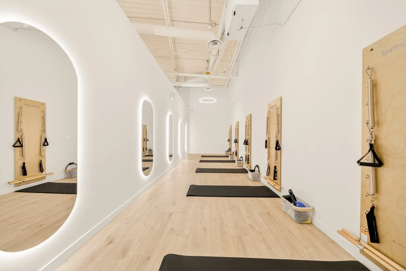 The Spring Wall room at Elin Pilates — wall units with mats and backlit arch mirrors